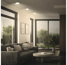 Salon moderne avec spots encastrés au plafond, design spacieux avec baies vitrées donnant sur un jardin verdoyant.