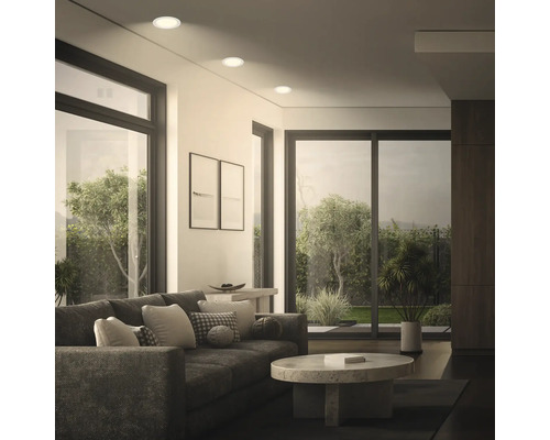 Salon moderne avec spots encastrés au plafond, design spacieux avec baies vitrées donnant sur un jardin verdoyant.