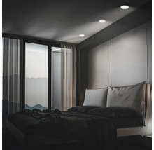 Chambre moderne avec spots encastrés au plafond, baies vitrées et vue sur les montagnes au crépuscule.