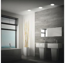 Salle de bain moderne avec double vasque, baignoire et trois spots encastrables LED ronds au plafond.