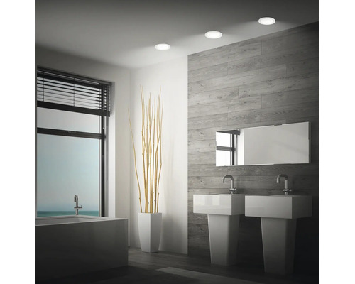 Salle de bain moderne avec double vasque, baignoire et trois spots encastrables LED ronds au plafond.
