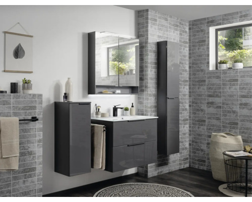 Ensemble de meubles de salle de bain gris moderne avec sous-vasque, armoire de toilette et deux colonnes sur un mur effet pierre.