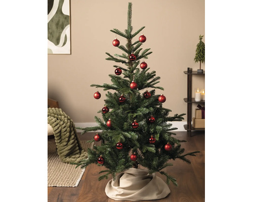 Sapin de Noël artificiel décoré de boules rouges dans un salon lumineux sur un parquet.