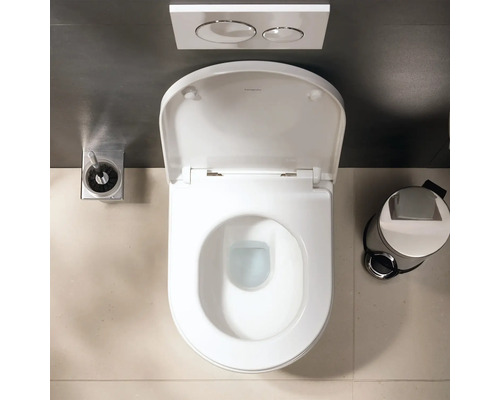 Toilette suspendue avec abattant ouvert vue de dessus, plaque de commande, brosse et poubelle à pédale dans une salle de bains moderne.