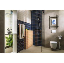 Salle de bains moderne avec douche à l'italienne, paroi en verre, motifs de carreaux géométriques, toilette suspendue et robinetterie chromée.