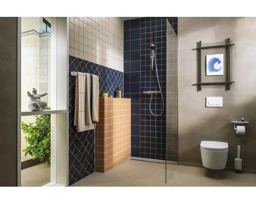 Salle de bains moderne avec douche à l'italienne, paroi en verre, motifs de carreaux géométriques, toilette suspendue et robinetterie chromée.