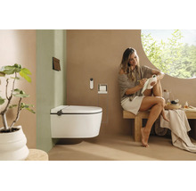 WC douche suspendu dans une salle de bains moderne et lumineuse avec une femme assise sur un banc en bois.