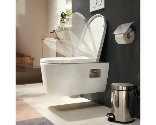 WC suspendu avec abattant à fermeture ralentie dans une salle de bains moderne avec poubelle à pédale et porte-papier toilette.