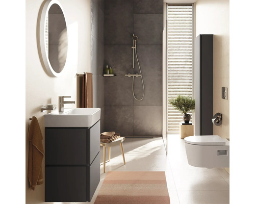 Salle de bains moderne avec meuble gris foncé, vasque blanche, miroir rond, douche à l'italienne et WC suspendu. Ambiance lumineuse et organisée.
