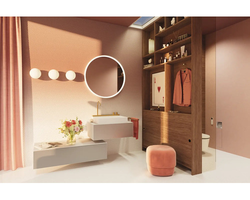 Salle de bains moderne et lumineuse avec lavabo suspendu, miroir LED rond, étagère en bois servant de cloison et accents roses comme le rideau et le pouf.