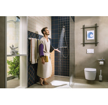 Salle de bains moderne et lumineuse avec douche ouverte, paroi en verre, toilette suspendue et murs carrelés.