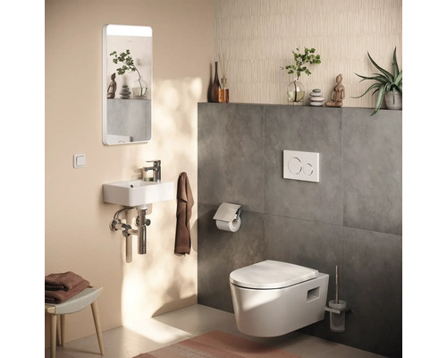 Toilettes d'invités modernes avec WC suspendu, lave-mains compact, miroir éclairé et plaque de déclenchement.
