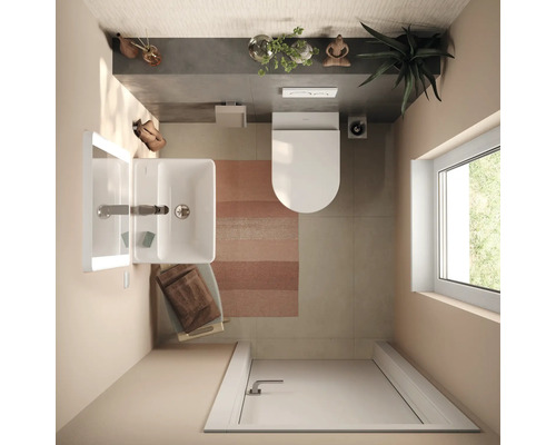 Vue de dessus d'une salle de bains moderne et lumineuse avec lavabo blanc, toilettes suspendues, tapis rayé et lumière naturelle par une fenêtre.