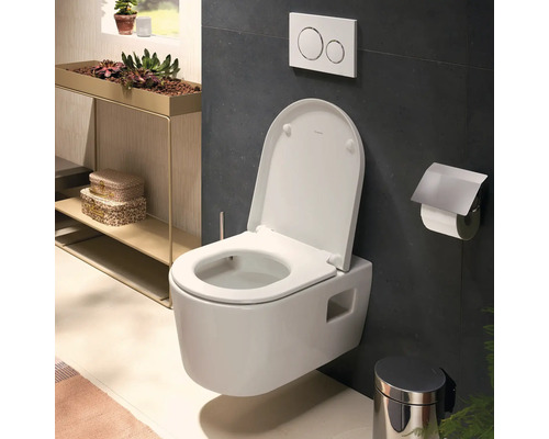 WC suspendu avec abattant ouvert, plaque de déclenchement, porte-rouleau et poubelle dans une salle de bains moderne.