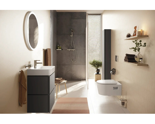 Salle de bains moderne avec meuble sous vasque, miroir rond éclairé, douche à l'italienne et toilette suspendue dans un design clair et ordonné.
