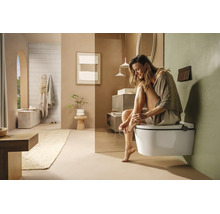 Salle de bains moderne et lumineuse avec WC suspendu, meubles minimalistes et décoration dans des tons terreux naturels.