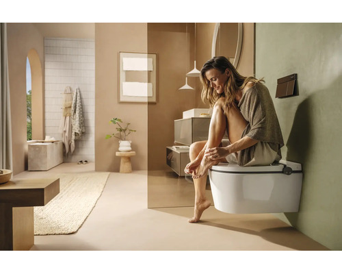 Salle de bains moderne et lumineuse avec WC suspendu, meubles minimalistes et décoration dans des tons terreux naturels.