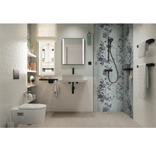 Salle de bains moderne et lumineuse avec WC suspendu, lavabo blanc, robinetterie noire et douche avec motif floral.