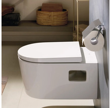 WC suspendu en céramique avec abattant fermé et porte-rouleau de papier toilette dans une salle de bains moderne et lumineuse.