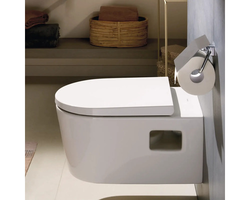 WC suspendu en céramique avec abattant fermé et porte-rouleau de papier toilette dans une salle de bains moderne et lumineuse.