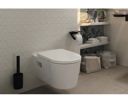 Salle de bains moderne avec WC suspendu blanc, brosse de toilette noire et porte-papier noir devant un mur à motifs.