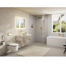 Salle de bains moderne et lumineuse avec WC suspendu, meuble vasque, miroir éclairé, douche à l'italienne et baignoire avec robinetterie dorée.