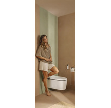 Salle de bains moderne avec WC douche suspendu, télécommande, porte-papier toilette intégré et une femme.