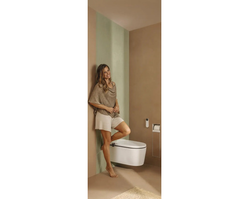 Salle de bains moderne avec WC douche suspendu, télécommande, porte-papier toilette intégré et une femme.