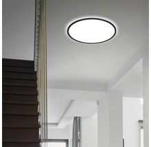 Moderne runde LED-Deckenleuchte in einem hellen Raum mit einer dunklen Holztreppe.