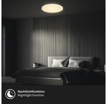 Runde LED-Deckenleuchte mit Nachtlichtfunktion in einem modern eingerichteten Schlafzimmer mit Wandpaneelen aus Holz.