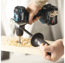 Perceuse-visseuse sans fil Makita 40 Volt avec poignée supplémentaire perçant un trou dans du bois avec des copeaux.