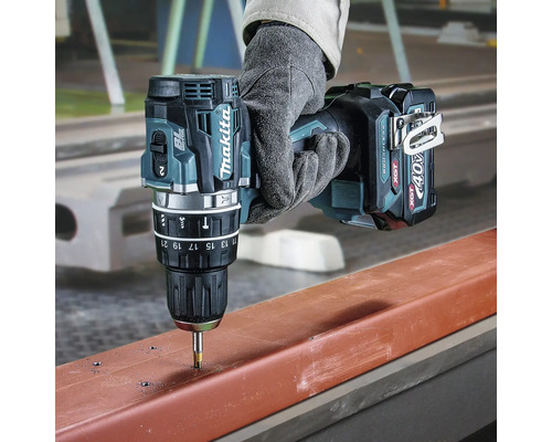 Perceuse-visseuse sans fil Makita 40 Volt XGT perçant un profilé métallique, tenue par une main avec gant de travail.