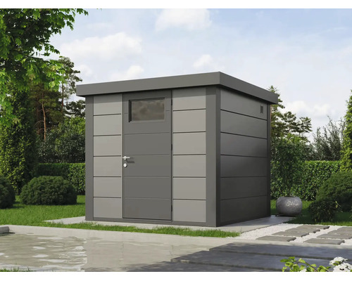 Abri de jardin moderne en métal gris avec toit plat et porte simple avec fenêtre dans un jardin avec pelouse, haies et bassin au premier plan.