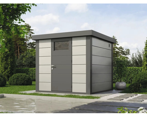 Abri de jardin moderne en métal avec toit plat et porte avec fenêtre dans un jardin aménagé.