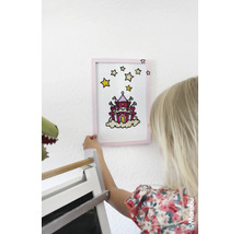 Ein Kind hält ein mit Glasmalfarbe gestaltetes Bild eines Schlosses in einem Rahmen an die Wand. Marabu Logo.