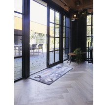 Tapis de sol avec motif de cœurs devant une porte vitrée ouverte sur un parquet clair.