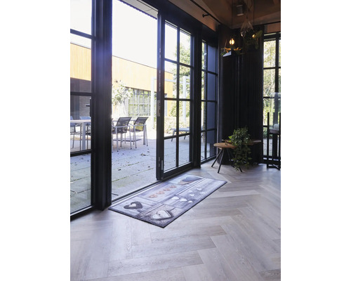 Tapis de sol avec motif de cœurs devant une porte vitrée ouverte sur un parquet clair.