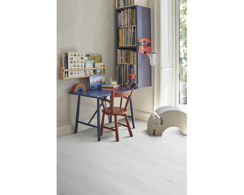 Chambre d'enfant lumineuse et organisée avec bureau en bois bleu, chaise rouge et étagères sur un sol stratifié clair aspect bois.