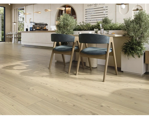 Revêtement de sol stratifié clair aspect bois dans un café moderne avec coin salon et plantes.
