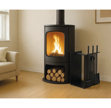 Poêle à bois noir moderne avec feu et compartiment à bûches dans un salon lumineux avec canapé et serviteur de cheminée.