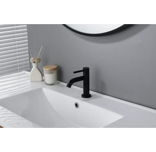 Mitigeur de lavabo noir sur un lavabo blanc dans une salle de bain moderne et lumineuse.