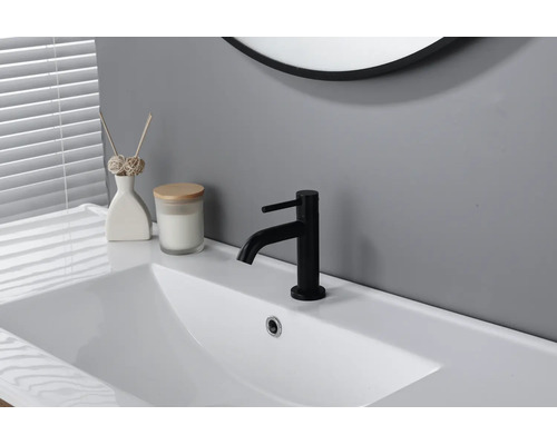 Mitigeur de lavabo noir sur un lavabo blanc dans une salle de bain moderne et lumineuse.