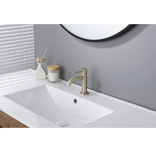 Salle de bain moderne lumineuse avec lavabo en céramique blanche, mitigeur doré et miroir rond.