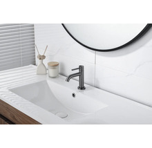 Salle de bains moderne et lumineuse avec lavabo rectangulaire blanc, mitigeur gris foncé, meuble sous-vasque en bois et carrelage aspect marbre.