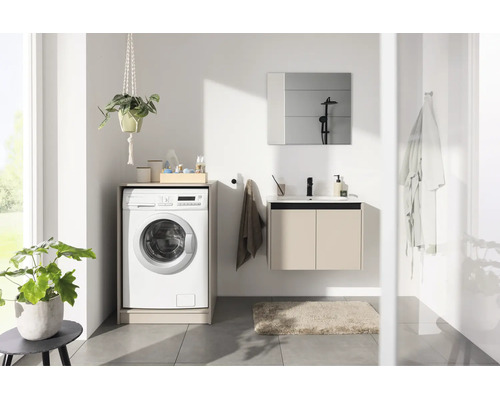 Salle de bains lumineuse avec lave-linge intégré dans un meuble, meuble sous-vasque suspendu avec lavabo et miroir.