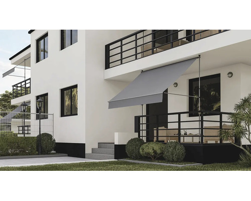 Graue Klemmmarkise auf einer Terrasse eines modernen weißen Hauses mit schwarzen Geländern und Garten.