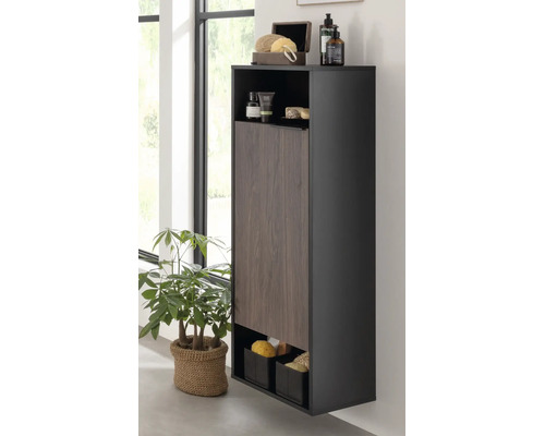 Armoire de salle de bain haute et moderne avec corps sombre, porte aspect bois et compartiments ouverts pour produits de soin.