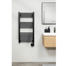 Sèche-serviettes électrique moderne noir avec thermostat numérique, monté à côté d'un meuble sous-vasque en bois dans une salle de bains claire.