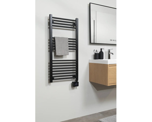Sèche-serviette noir avec thermostat numérique dans la salle de bains à côté d'un meuble sous-vasque en bois avec lavabo et miroir.