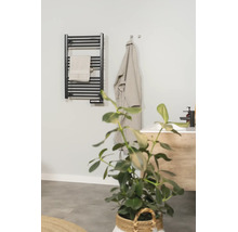 Radiateur sèche-serviettes électrique noir dans une salle de bains moderne avec serviette, peignoir et lavabo.